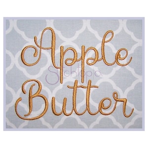 Pode incluir: Desenho bordado em fio dourado sobre um fundo azul claro. O desenho diz "Apple Butter" em uma fonte cursiva.
