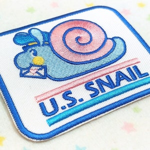 May include: A blue and pink snail with a mailbag and a hat, embroidered on a white patch with the text "U.S. SNAIL" in blue, pink, and turquoise.