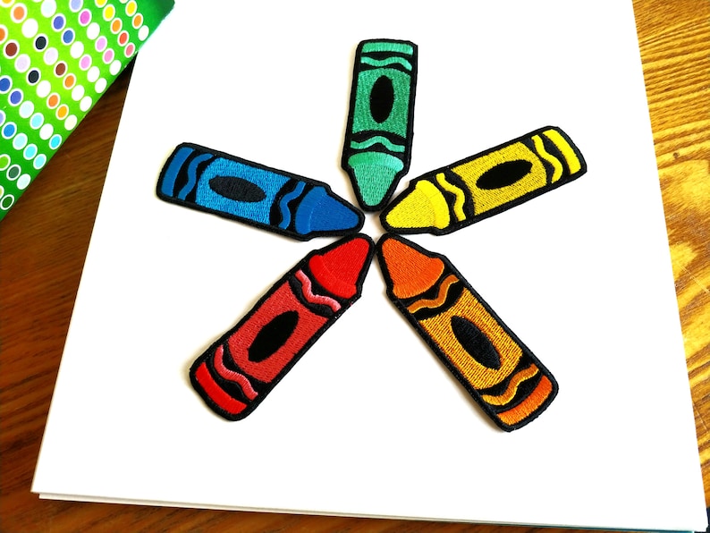 Op de afbeelding: Zes kleurrijke waskrijt-patches in de vorm van een ster. De waskrijtjes zijn rood, oranje, geel, groen, blauw en paars.