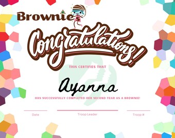 May include: A certificate with a colorful geometric pattern border. The certificate reads "Brownies Congratulations! This certifies that Ayanna has successfully completed her second year as a Brownie!" with spaces for the date, troop leader, and troop number.