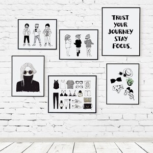 May include: A white brick wall with black framed prints. The prints feature illustrations of people, clothing, and text. One print says "Trust your journey stay focus".