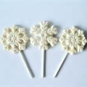 May include: Three white snowflake lollipops on a white background.