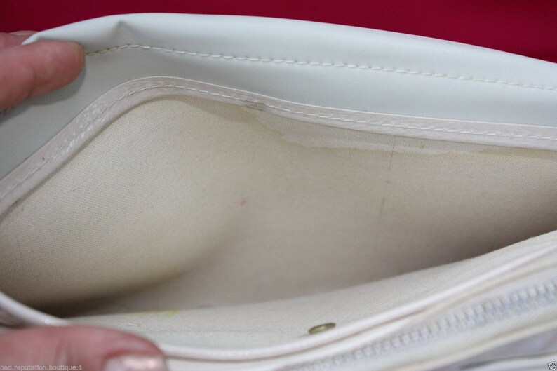 May include: A white fabric makeup bag with a zipper closure. The bag is open and the inside is visible.