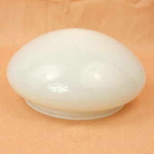 May include: A smooth, white, dome-shaped glass light fixture shade. The object features a rounded, opaque surface with a circular base designed for attachment to a lighting fixture. The material appears to be translucent white glass.