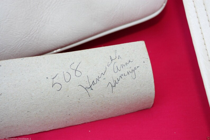 May include: A close-up of a white paper label with handwritten text that reads "508 Janine Anna Werneriger."