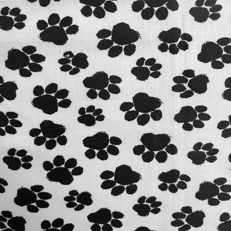 May include: White fabric with a repeating pattern of black paw prints.
