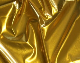 May include: A close-up of a gold fabric with a shiny, metallic finish. The fabric is draped and folded, creating soft, flowing lines.