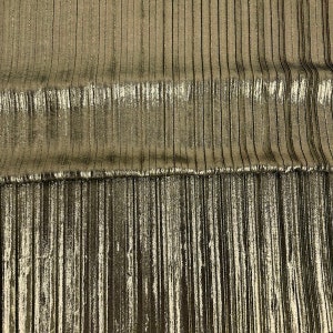 May include: Gold metallic fabric with vertical pleats. The fabric has a subtle sheen and a slightly textured surface.