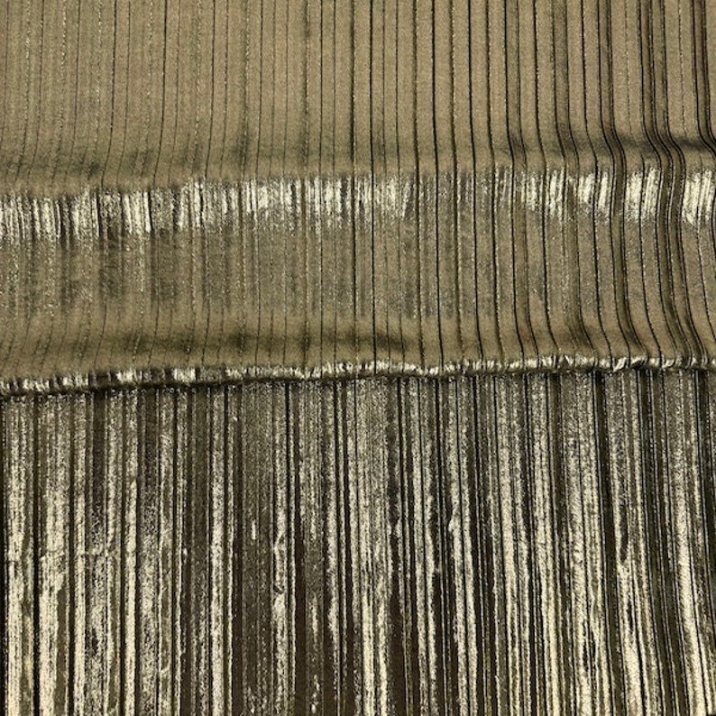 May include: Gold metallic fabric with vertical pleats. The fabric has a subtle sheen and a slightly textured surface.