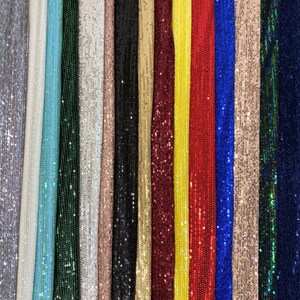 May include: A variety of sequined fabrics in different colors, including silver, light blue, green, white, beige, black, gold, burgundy, yellow, red, blue, and teal.