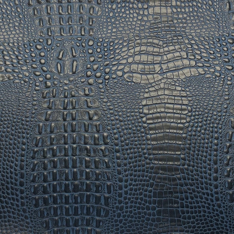 Puede incluir: Primer plano de una textura de piel de cocodrilo artificial de color azul oscuro. La textura est&aacute; estampada con un patr&oacute;n repetitivo de escamas.