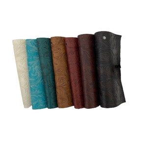 May include: A set of seven different coloured leather swatches with an embossed floral pattern. The swatches are arranged in a row from left to right, with the lightest colour on the left and the darkest colour on the right.
