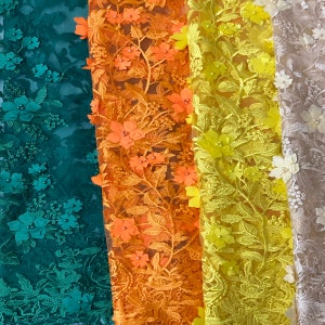 Puede incluir: Cuatro tipos diferentes de tela de encaje con patrones florales. Las telas son verde, naranja, amarilla y beige.