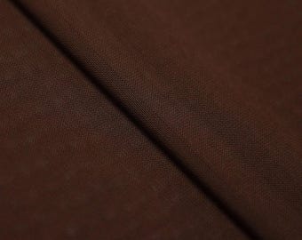 May include: A solid dark brown fabric with a visible woven texture. The material is folded diagonally, creating a soft shadow along the crease that highlights the consistent deep brown color and the fine, uniform weave of the textile surface.