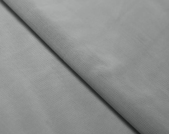 May include: Close-up of a light gray tulle fabric with a fine mesh texture. The fabric is folded in half, showing the smooth surface and the delicate weave.