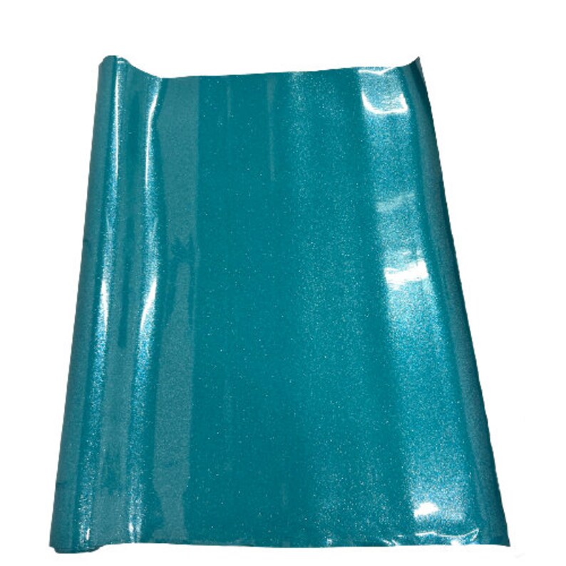 May include: A roll of teal glitter vinyl with a shiny, iridescent finish. The vinyl is rolled up and ready to be used for crafting projects.