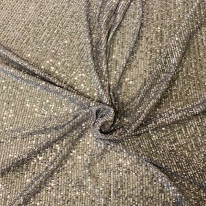 May include: Silver sequined fabric with a subtle vertical pattern. The sequins are small and closely spaced, creating a shimmering effect.