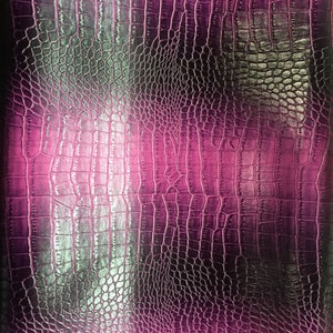 May include: A close-up of a textured, pink faux leather material with a crocodile or alligator skin pattern. The color transitions from a bright pink to a darker, almost black shade, creating a gradient effect. The surface has a glossy finish.