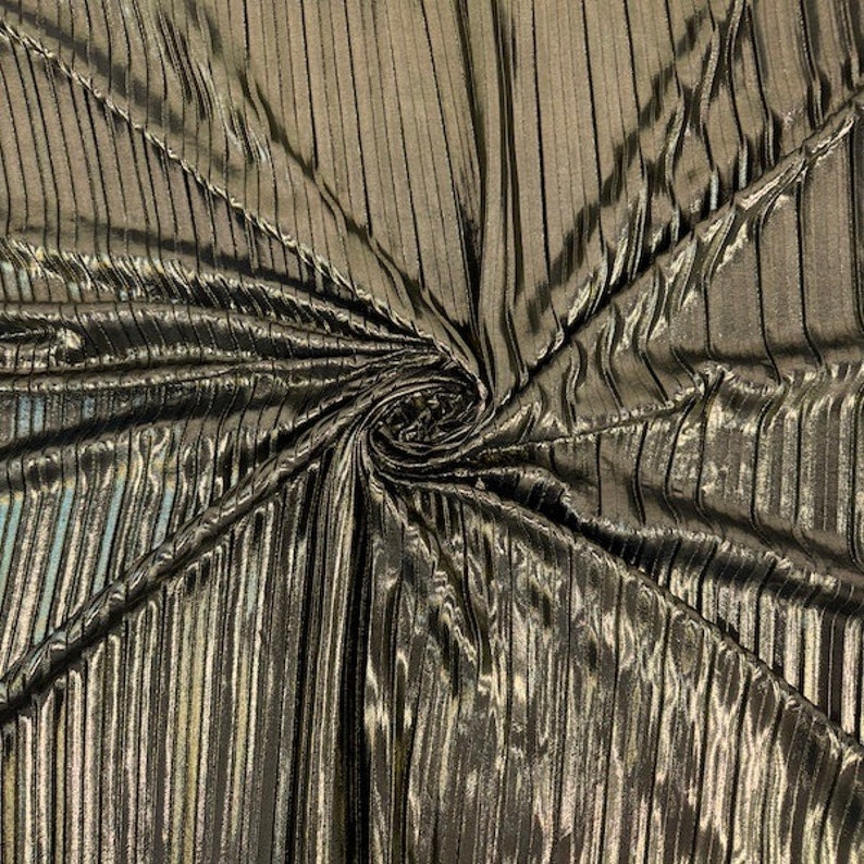 May include: A close-up of a metallic gold fabric with vertical pleats. The fabric has a subtle sheen and a soft, drapey texture.