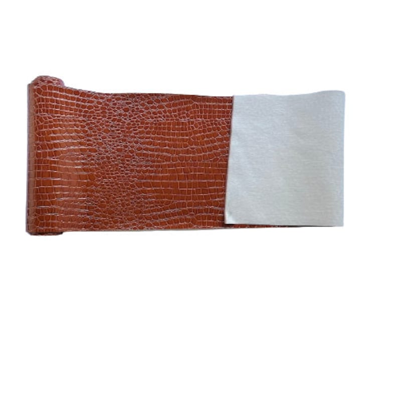 May include: A roll of brown faux crocodile embossed leather with a white backing.