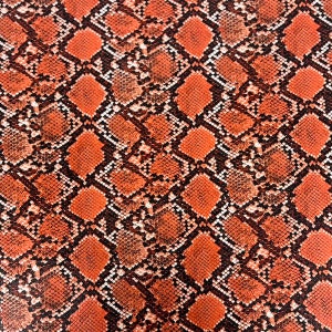 May include: Orange and black snakeskin pattern fabric. The pattern is a repeating design of overlapping scales.
