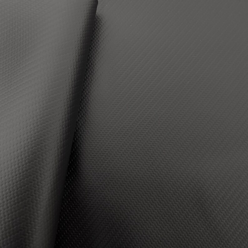 May include: Close-up of black textured fabric with a subtle diamond pattern. The fabric is folded in half, showing the texture on both sides.