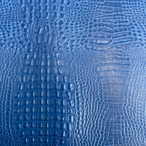 May include: Blue faux crocodile embossed leather texture. The texture is shiny and has a subtle sheen.