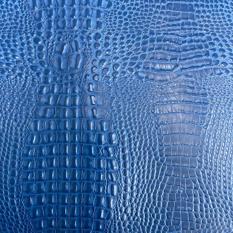 May include: Blue faux crocodile embossed leather texture. The texture is shiny and has a subtle sheen.