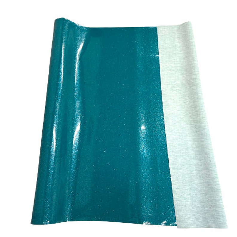 May include: A teal green fabric with a glittery finish, folded in half, next to a white fabric.