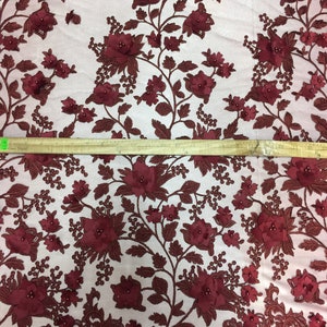 Puede incluir: Tela de encaje floral burdeos con flores 3D y detalles de perlas. La tela tiene un fondo de malla delicado.