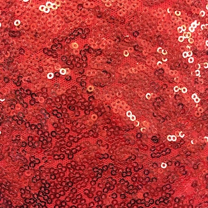 May include: Red fabric covered in small, round sequins. The sequins are tightly packed together, creating a shimmering effect.
