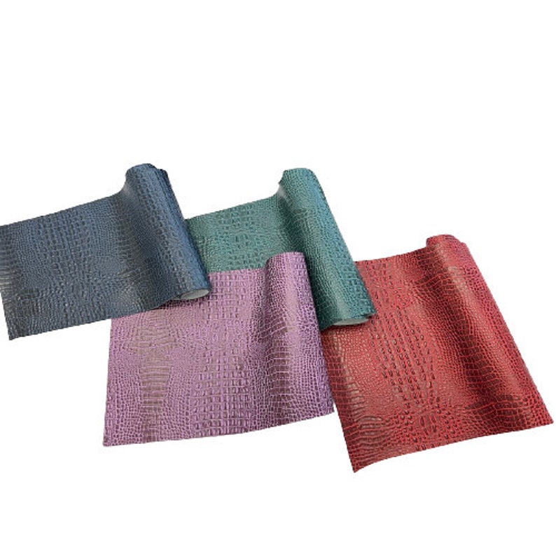 Puede incluir: Cuatro rollos de piel sint&eacute;tica con un patr&oacute;n de piel de cocodrilo. Los rollos son de color turquesa, rosa, rojo y azul.