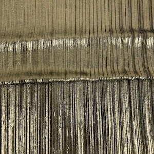 May include: A metallic gold fabric featuring a vertical pleated texture. The material displays a shimmering, reflective surface with consistent, narrow, straight lines running from top to bottom, creating a structured and uniform appearance.