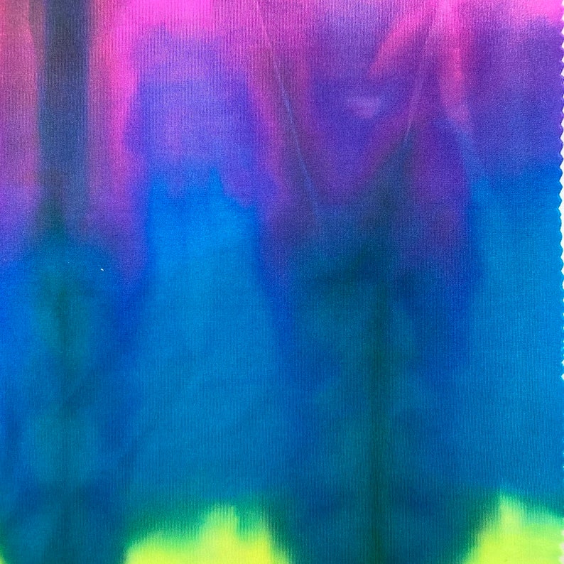 May include: A tie-dye fabric with a gradient of pink, purple, blue, and green colors. The fabric has a soft, smooth texture.