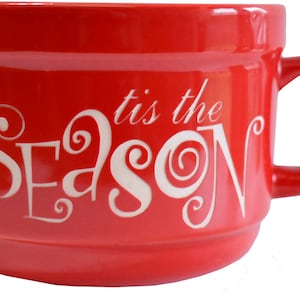 May include: Red ceramic mug with a white inscription that reads "'tis the season" in a stylised font.