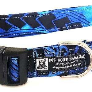 May include: A blue dog collar with a black plastic buckle and a silver metal D-ring. The collar features a Hawaiian-style pattern in shades of blue and black. The label reads "DOG GONE HAWAIIAN".