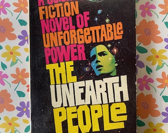 Può includere: Un libro tascabile vintage intitolato The Unearth People di Kris Neville. La copertina nera presenta testo in rosa, arancione e giallo, un'illustrazione di un volto umano verde e immagini spaziali. Editore Belmont, numero 92-611, 50 centesimi.