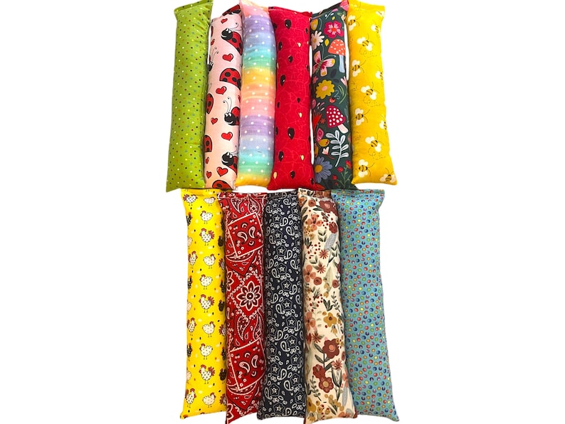 May include: Eleven rectangular fabric tubes arranged in two rows. The patterns include green with dots, ladybugs and hearts, rainbow ombre, red with black spots, floral with mushrooms, yellow with bees, yellow with chickens, red paisley, navy paisley, floral, and blue dots.