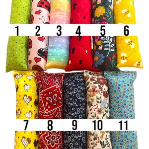 May include: Eleven rectangular fabric pouches arranged in two rows, numbered 1 through 11. Patterns include green polka dots, ladybugs, rainbow gradients, red watermelon seeds, floral prints, yellow bees, chickens, red and blue paisley, and colorful dots.