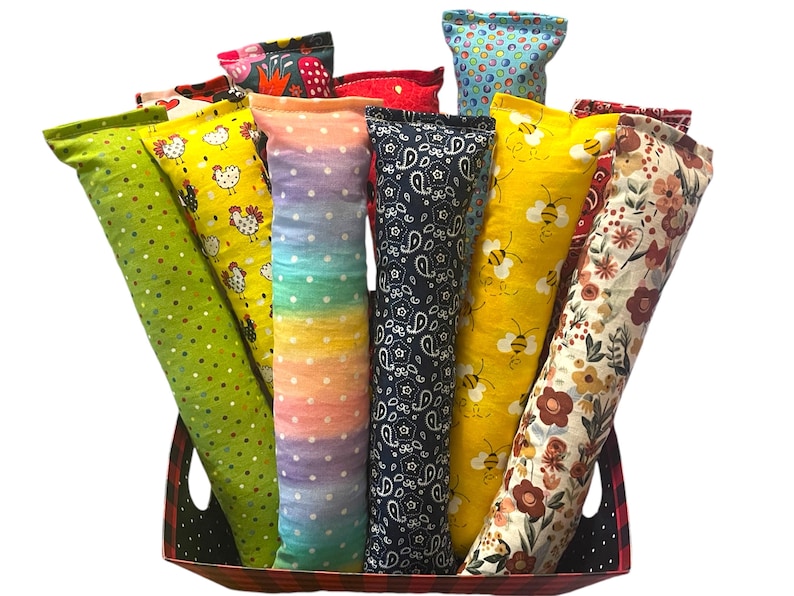 May include: A collection of long, cylindrical fabric pouches in a variety of patterns and colors, including green with dots, yellow with chickens, rainbow with white dots, navy blue with paisley, yellow with bees, and floral prints in a basket.