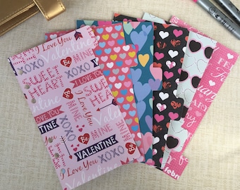 May include: A set of six Valentine's Day themed planner dividers with pink, blue, black, and white hearts and text. The dividers feature the text "I Love You", "Valentine", "Sweet Heart", "Be Mine", "XOXO", and "February".