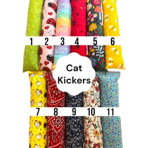 May include: Eleven rectangular fabric cat kickers arranged in two rows, labeled 1 through 11. Patterns include green dots, ladybugs, rainbow stripes, red, floral, bees, chickens, red paisley, navy paisley, autumn leaves, and blue multi-colored dots.