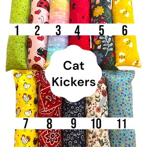 May include: Eleven rectangular fabric cat kickers arranged in two rows, labeled 1 through 11. Patterns include green dots, ladybugs with hearts, rainbow stripes, red watermelon seeds, floral garden, yellow bees, chickens, red and blue paisley, and dots.