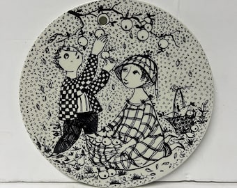 May include: Black and white illustration of two people picking apples from a tree. The woman is wearing a plaid dress and a hat. The man is wearing a checked shirt and trousers. They are both holding baskets of apples.