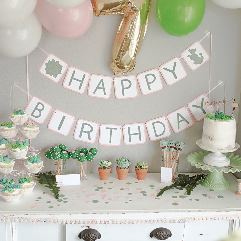 May include: A green and pink cactus themed birthday party with a banner that says "Happy Birthday". The table is decorated with green and pink confetti, cupcakes, and cactus cake pops.