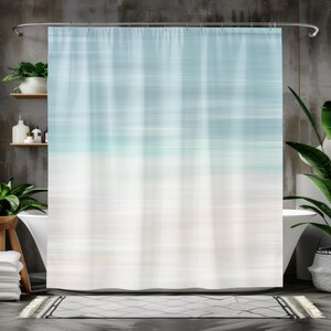 May include: A white and blue abstract shower curtain with a blurred horizontal stripe pattern. The curtain is hanging in a bathroom with a white bathtub and a gray tiled wall.