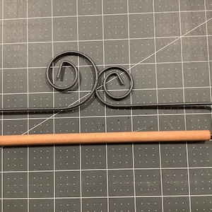 May include: A black metal towel rack with a decorative scroll design and a wooden dowel.