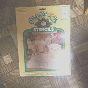 May include: A pack of Cabbage Patch Kids stencils. The pack is yellow with green and red accents. The pack features a Cabbage Patch Kid doll and the text "Cabbage Patch Kids Stencils".