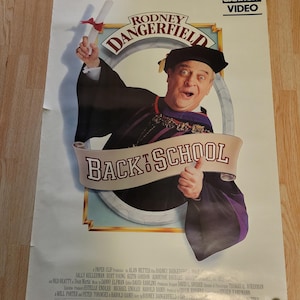 Może przedstawiać: Plakat filmowy w stylu vintage do filmu "Back to School" z Rodneym Dangerfieldem w todze. Plakat ma logo HBO Cannon Video i tytuł filmu dużymi literami. Plakat jest podtrzymywany przez dwie dyskietki.