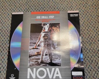May include: A laser videodisc with the title "Nova" and the phrase "One Small Step" printed on the cover. The cover features an astronaut on the moon. The disc is a rainbow color.